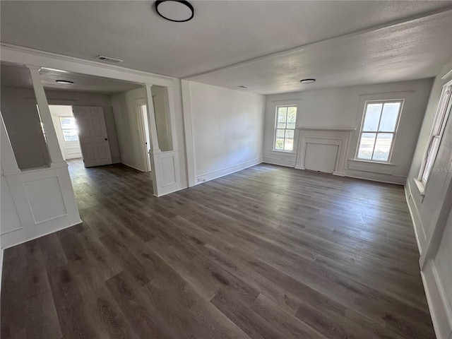 interior space with dark wood finished floors, visible vents, decorative columns, and baseboards