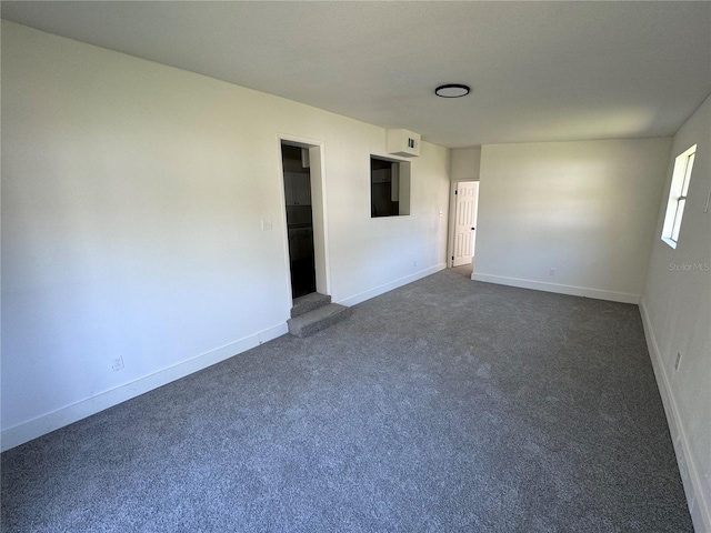 empty room featuring dark colored carpet and baseboards