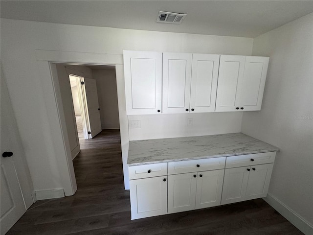 kitchen with visible vents, baseboards, dark wood-type flooring, light stone countertops, and white cabinetry