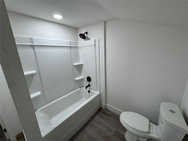 bathroom featuring washtub / shower combination, wood finished floors, toilet, and baseboards