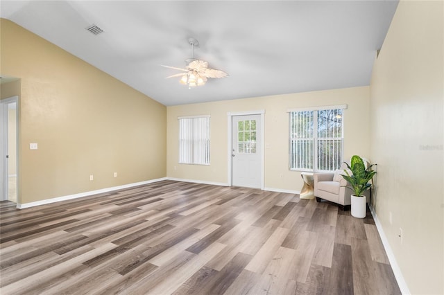 interior space with lofted ceiling, visible vents, baseboards, and wood finished floors