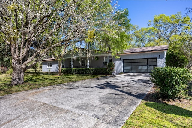 ranch-style home featuring a front yard, brick siding, a garage, and driveway