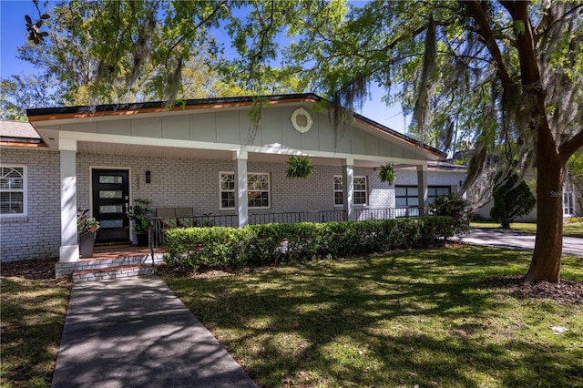 view of front of house featuring brick siding, a porch, and a front yard