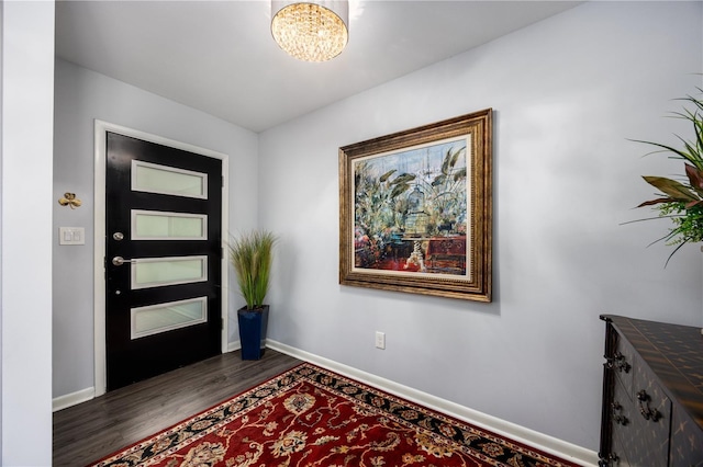 entrance foyer with dark wood finished floors, a chandelier, and baseboards