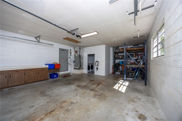 garage featuring heating unit, concrete block wall, a garage door opener, and separate washer and dryer