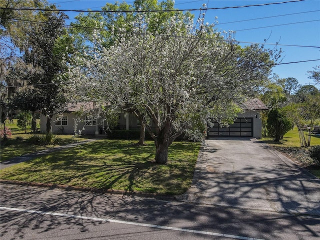 obstructed view of property with a front yard, an attached garage, driveway, and stucco siding