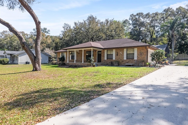 view of front of home featuring covered porch, a front lawn, and brick siding