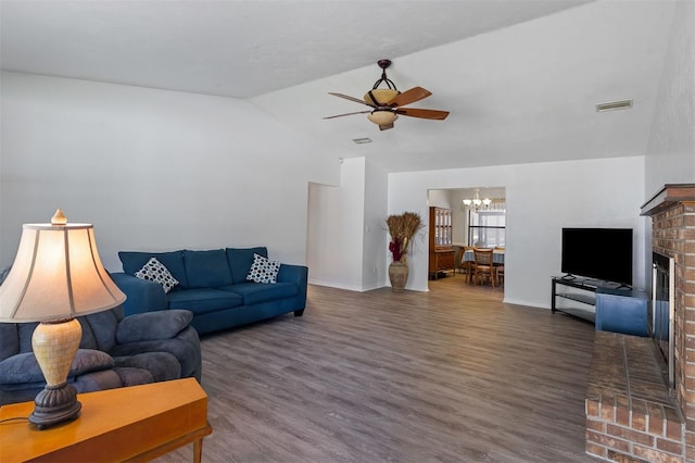 living area featuring lofted ceiling, ceiling fan with notable chandelier, wood finished floors, and visible vents