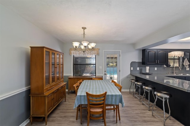 dining space featuring an inviting chandelier, light wood-style flooring, and baseboards