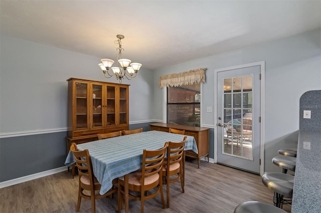 dining room with a chandelier, wood finished floors, and wainscoting