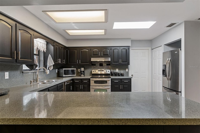 kitchen featuring visible vents, light stone counters, appliances with stainless steel finishes, a sink, and backsplash