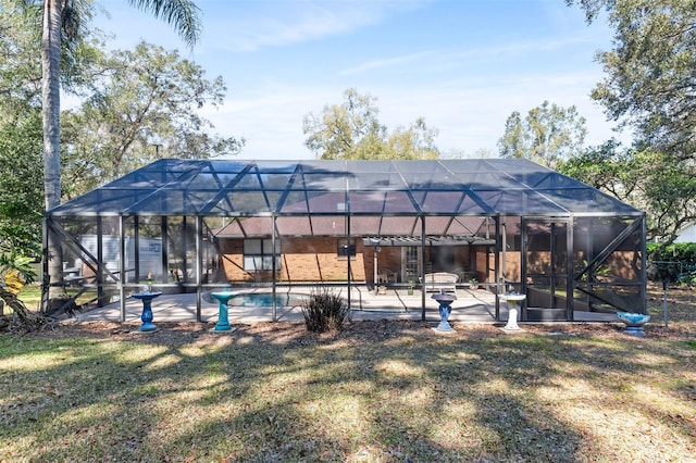 rear view of property with glass enclosure, a patio area, and an outdoor pool