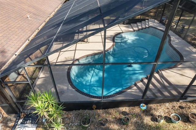 view of swimming pool featuring glass enclosure