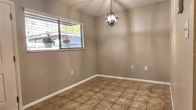 empty room featuring baseboards, a chandelier, and tile patterned floors