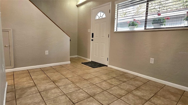 tiled foyer featuring baseboards and a textured wall