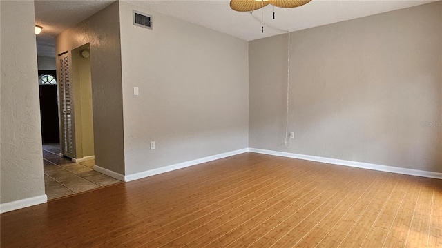 spare room with a ceiling fan, baseboards, visible vents, and wood finished floors