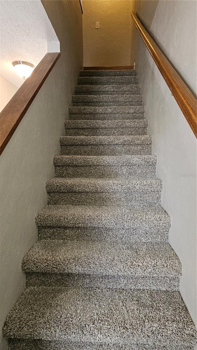 staircase featuring a textured wall