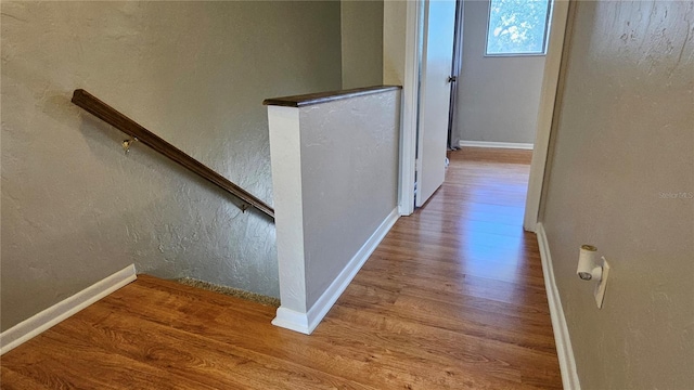 corridor with a textured wall, baseboards, and wood finished floors