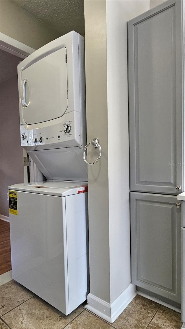 clothes washing area with laundry area, stacked washer / dryer, and baseboards