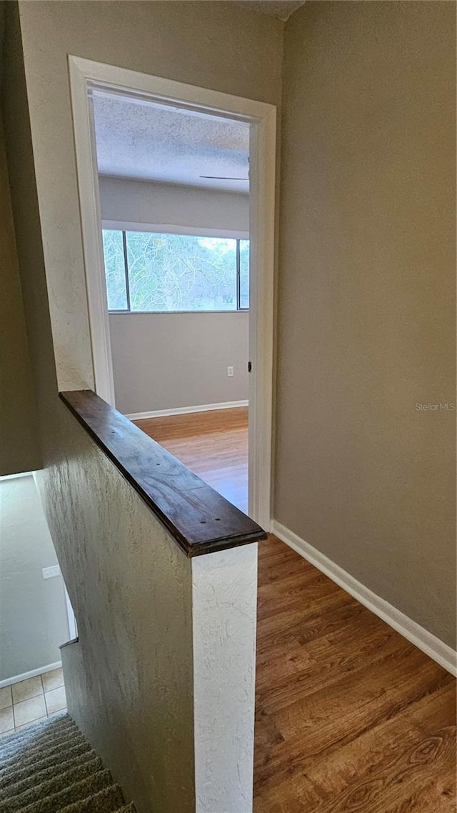 hall with baseboards and wood finished floors