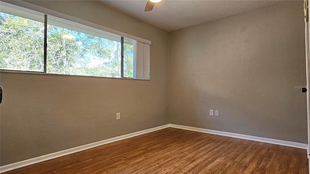 spare room with wood finished floors, a ceiling fan, and baseboards