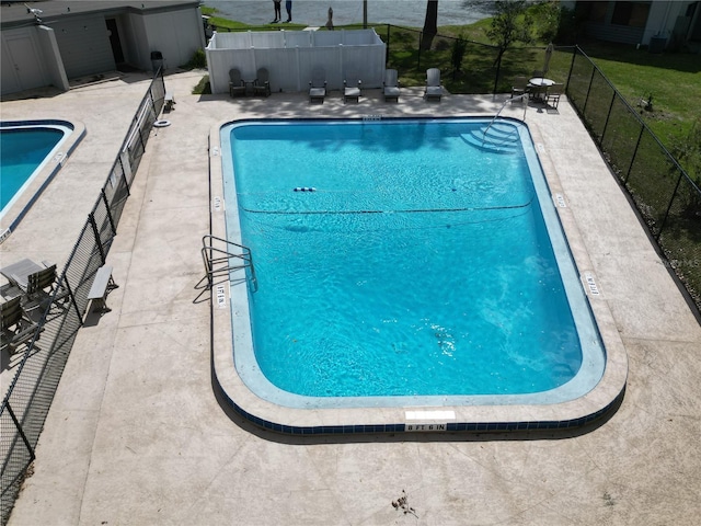 community pool with a patio area and fence