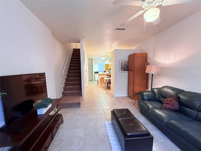 living room with stairway, visible vents, a ceiling fan, and light tile patterned flooring