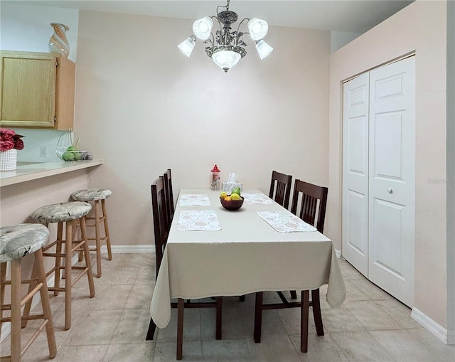 dining space with a chandelier, baseboards, and light tile patterned floors