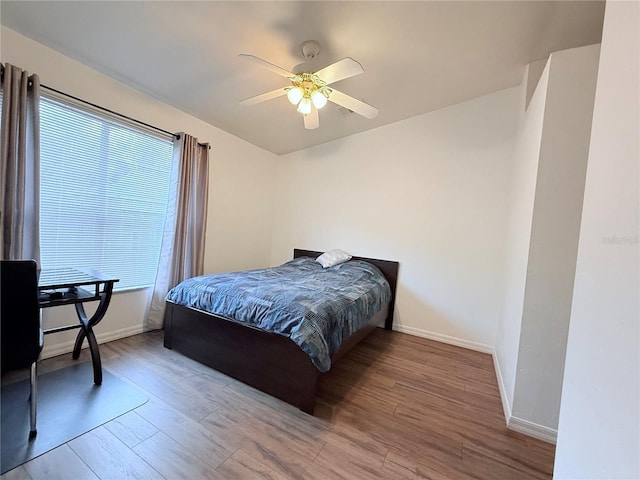 bedroom featuring a ceiling fan, baseboards, and wood finished floors