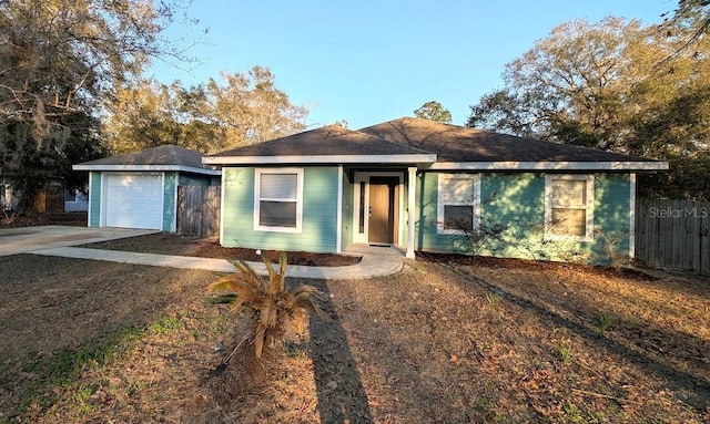 ranch-style house with concrete driveway, fence, a detached garage, and an outdoor structure