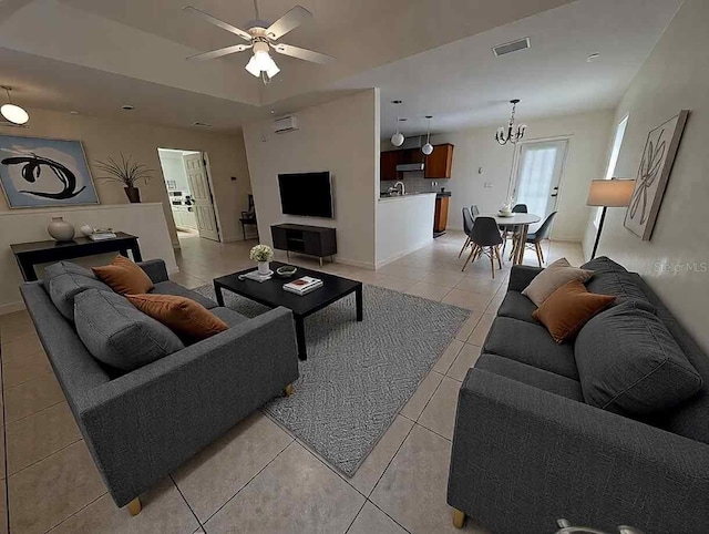 living area with light tile patterned floors, baseboards, visible vents, and ceiling fan with notable chandelier