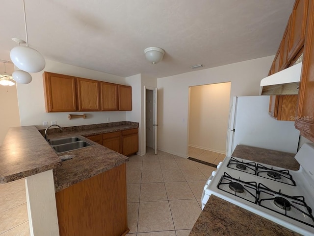 kitchen with brown cabinetry, a sink, white appliances, a peninsula, and under cabinet range hood