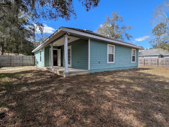 back of house with a fenced backyard and a patio