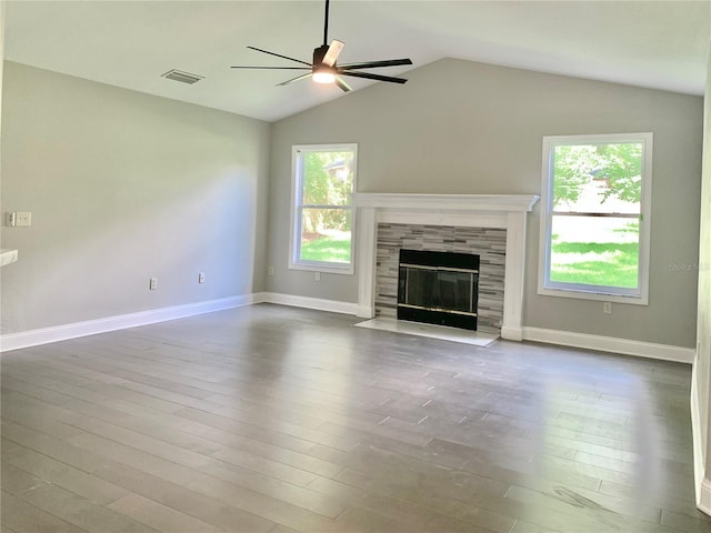 unfurnished living room with a tiled fireplace, wood finished floors, visible vents, and a ceiling fan