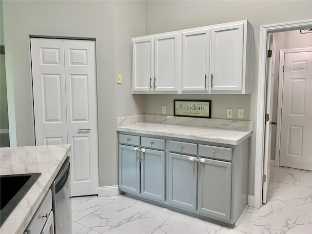 kitchen with marble finish floor, stainless steel dishwasher, a sink, light stone countertops, and baseboards