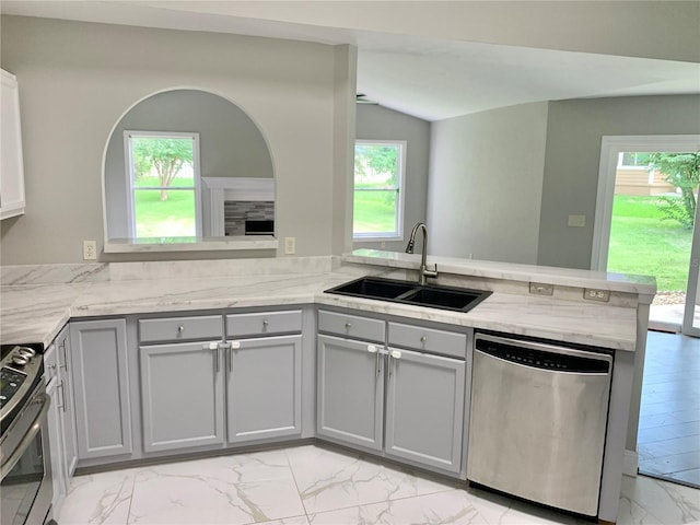 kitchen featuring gray cabinetry, stainless steel appliances, a peninsula, a sink, and marble finish floor