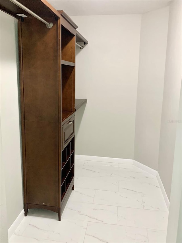 walk in closet featuring marble finish floor