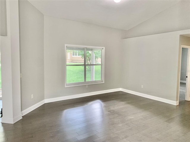 spare room with dark wood-style floors, baseboards, and vaulted ceiling