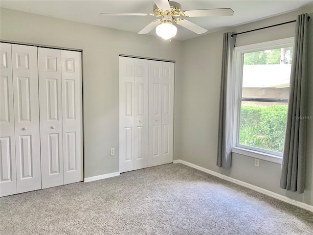 unfurnished bedroom featuring baseboards, ceiling fan, carpet, and multiple closets