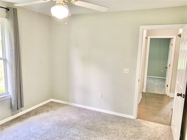 carpeted empty room with a ceiling fan and baseboards