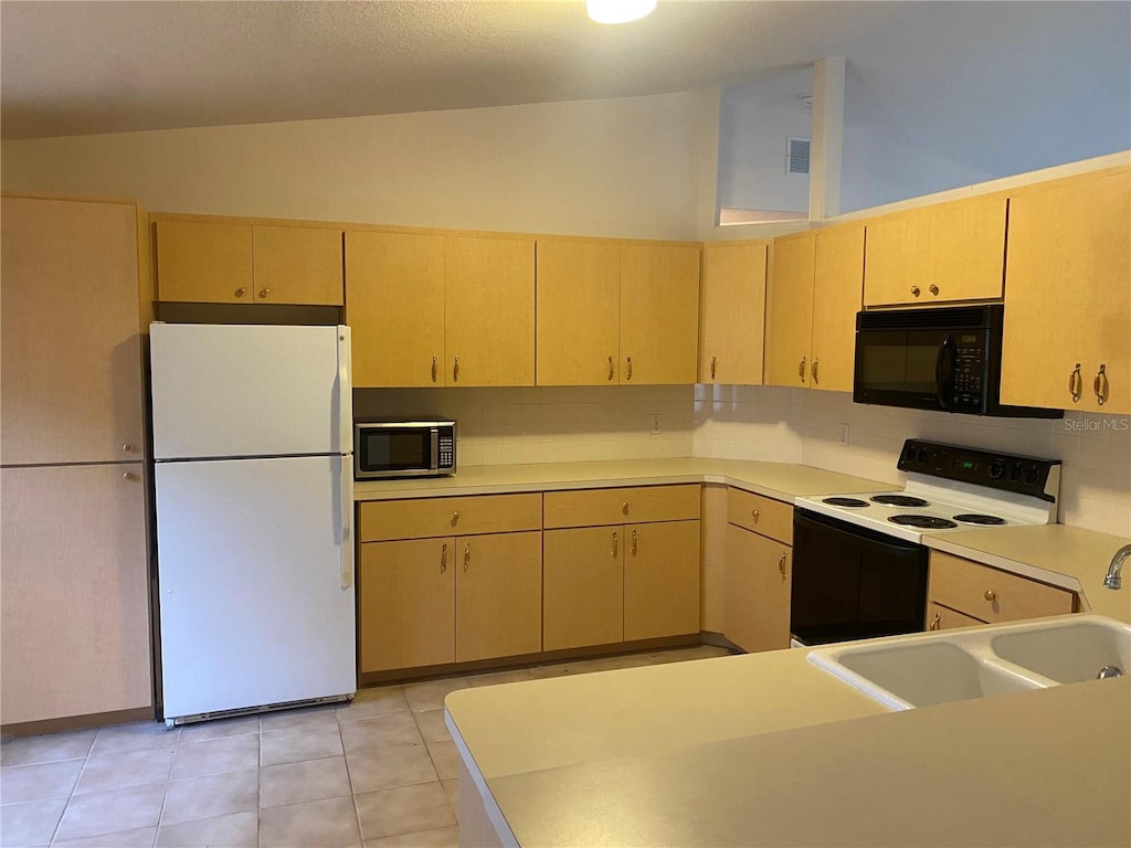 kitchen with black microwave, range with electric stovetop, light countertops, freestanding refrigerator, and stainless steel microwave