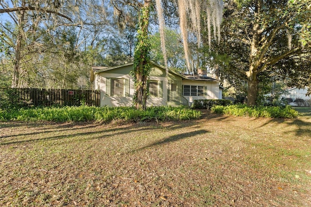 view of front of house with a chimney, fence, and a front yard