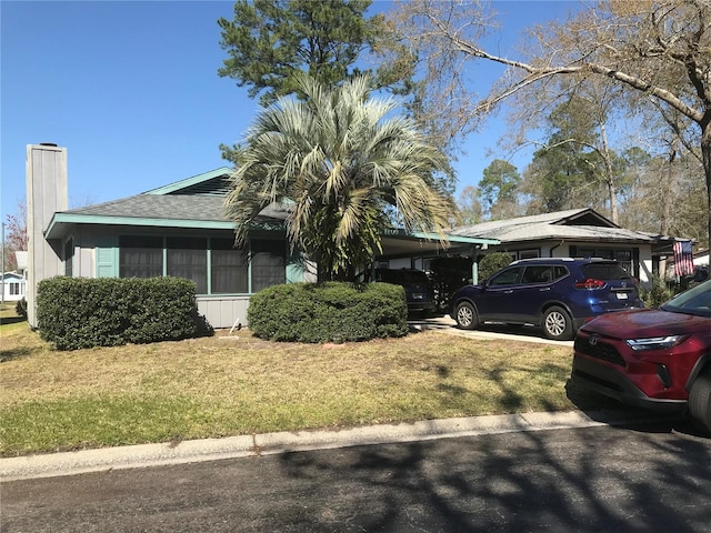 view of front of home featuring a carport, roof with shingles, a front lawn, and a chimney