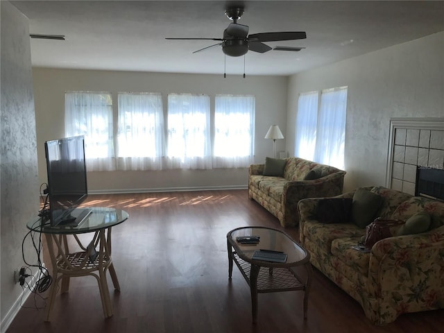 living area with wood finished floors, a ceiling fan, and baseboards