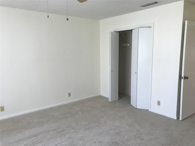 unfurnished bedroom with a closet, carpet, visible vents, and baseboards