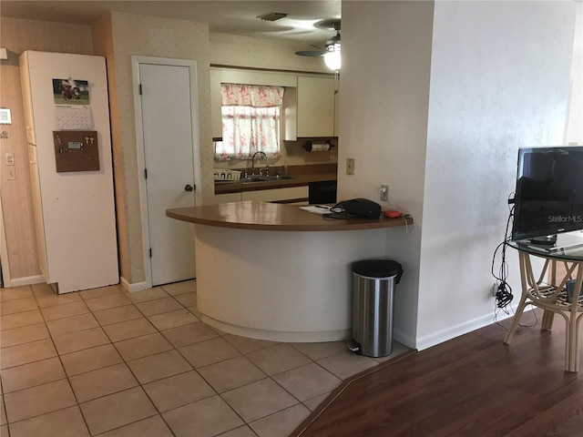 kitchen with ceiling fan, a sink, visible vents, and baseboards