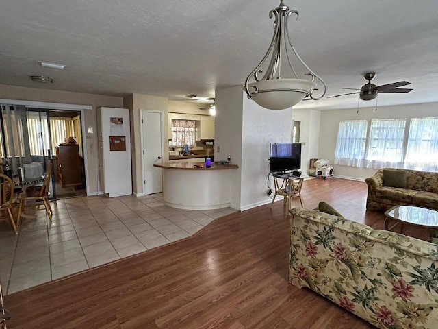living area with baseboards, wood finished floors, and ceiling fan