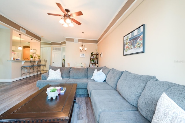 living area featuring ornamental molding, visible vents, and wood finished floors