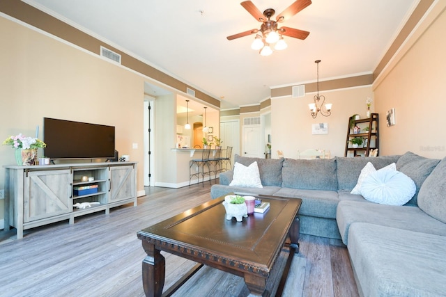 living room with visible vents, crown molding, and wood finished floors