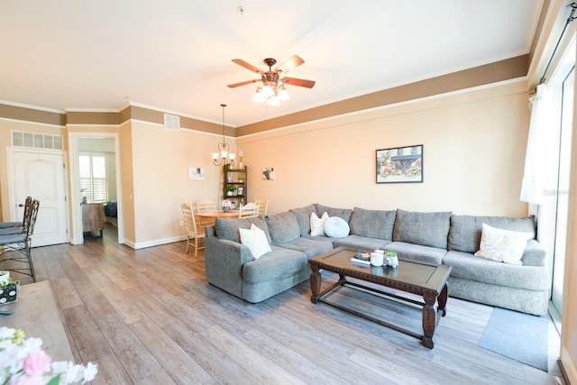 living area with crown molding, visible vents, light wood-type flooring, baseboards, and ceiling fan with notable chandelier